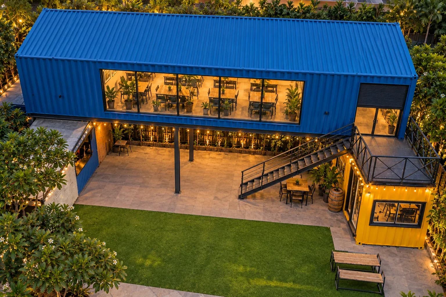 Illustrative render of a stacked container cafe concept seen from above, with a lawn and outdoor seating