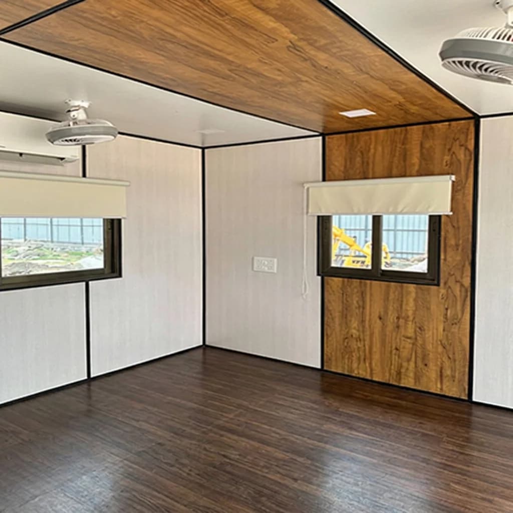 Inside a customized container office — laminated wall panels, wooden-finish false ceiling, vinyl flooring and ceiling fans