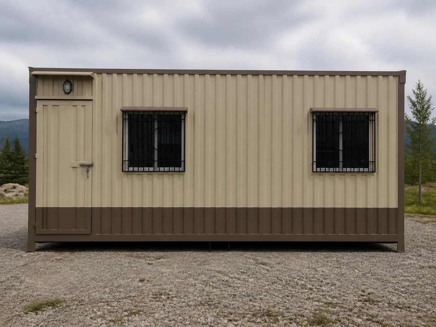 Portable cabin in Gummidipoondi — illustrative render of a beige container-style portable cabin with ribbed steel walls, a brown frame and lower band, a steel door with an outdoor light under a small hood, and two grilled windows under brown hoods, on a gravel yard