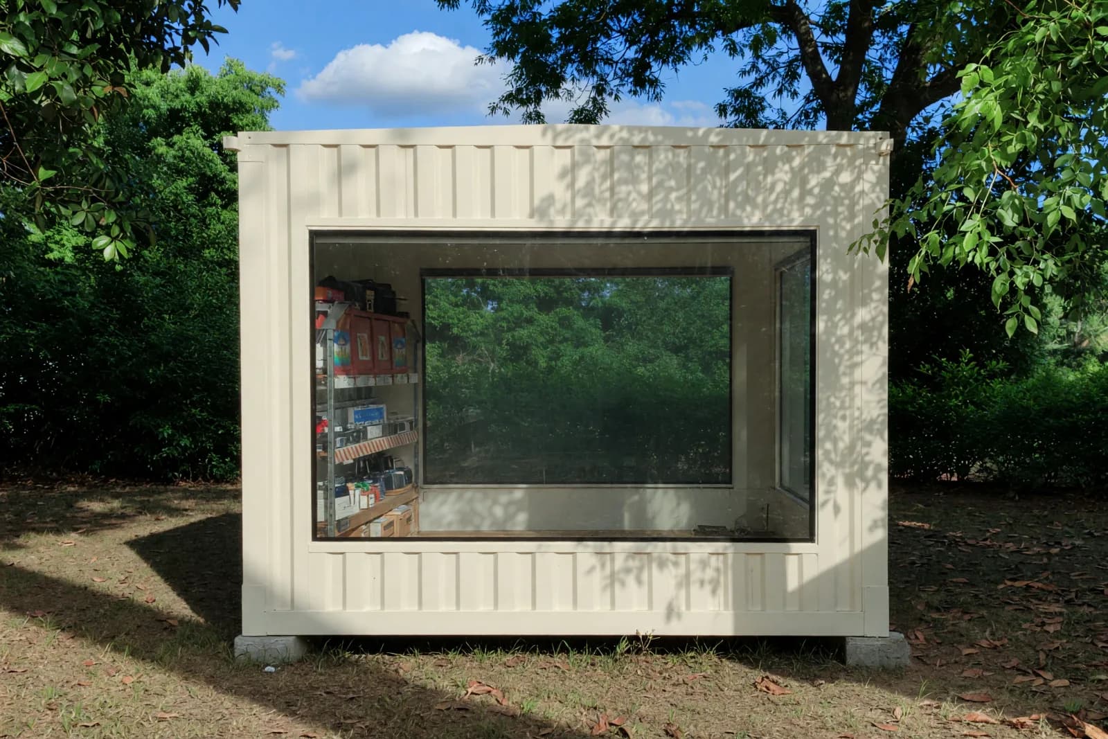 Illustrative render of the portable shop cabin's glazed side, with display shelving visible inside